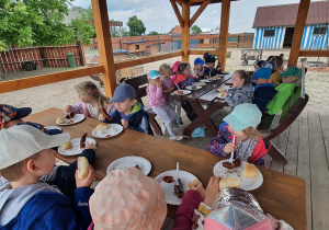 Dzieci jedzą kiełbaskę z grila.
